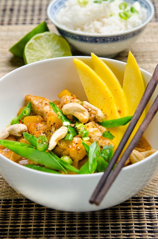 Curry mit Mango, Hähnchen und Kaiserschoten in der Schüssel, dekoriert mit Essstäbchen , Limetten und Reis