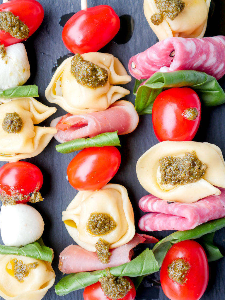 Bunte Nudelsalat-Spieße als schneller Fingerfood für das Party-Buffet - die Salatspieße mit Tortellini, Tomaten, Mozzarella, Basilikum und grünem Pesto sind ruckzuck zubereitet und eine prima Idee für das Partybuffet GAUMENFREUNDIN FOODBLOG #nudelsalat #silvester #picknick #buffet #rezept #fingerfood #snack #kinder #tomaten #mozzarella #pesto