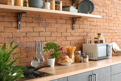 Lebensmittel für den Vorrat auf Regal in Küchenzeile mit Backsteinwand