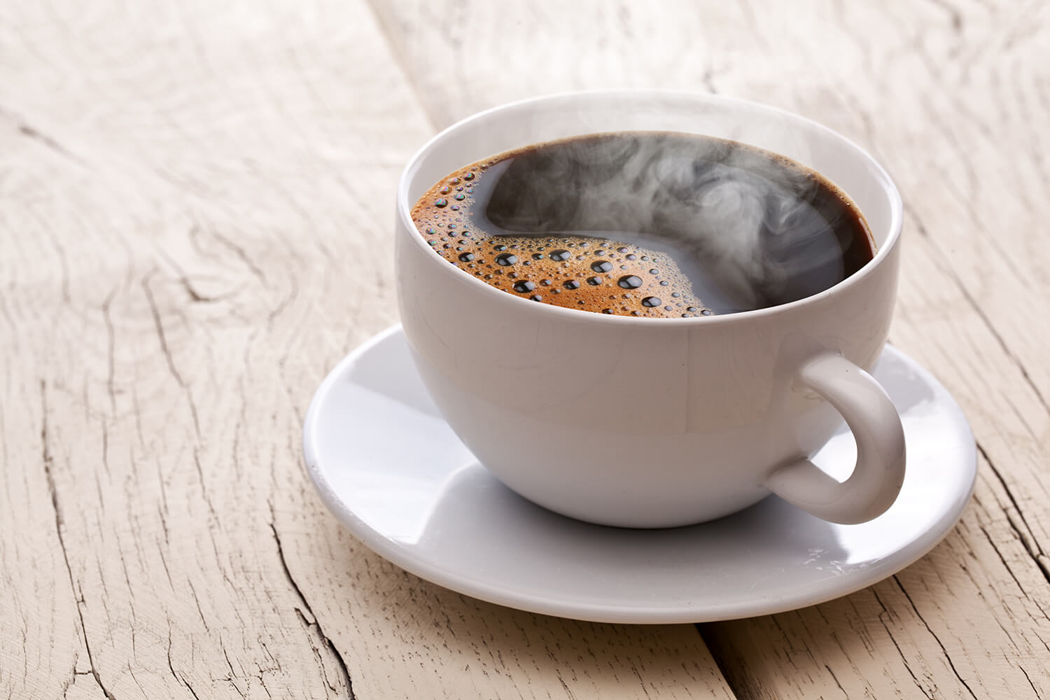 Tasse heisser Kaffee auf Holztisch