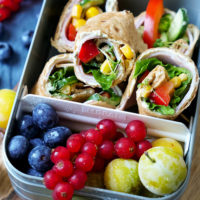 Lunchbox für die Schule mit Schinken-Wraps und Obst gefüllt