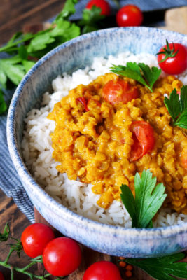 Rote Linsen-Curry mit Kokosmilch, Tomaten und Reis auf dem Teller