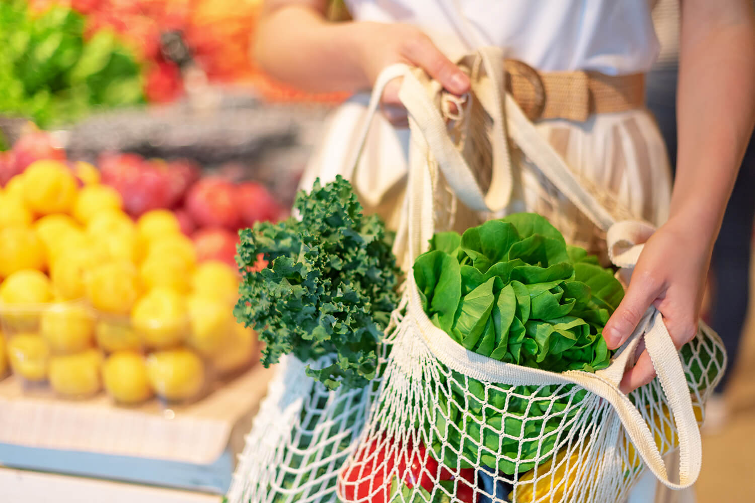 Frau mit Gemüsenetz beim verpackungsfreien Einkauf