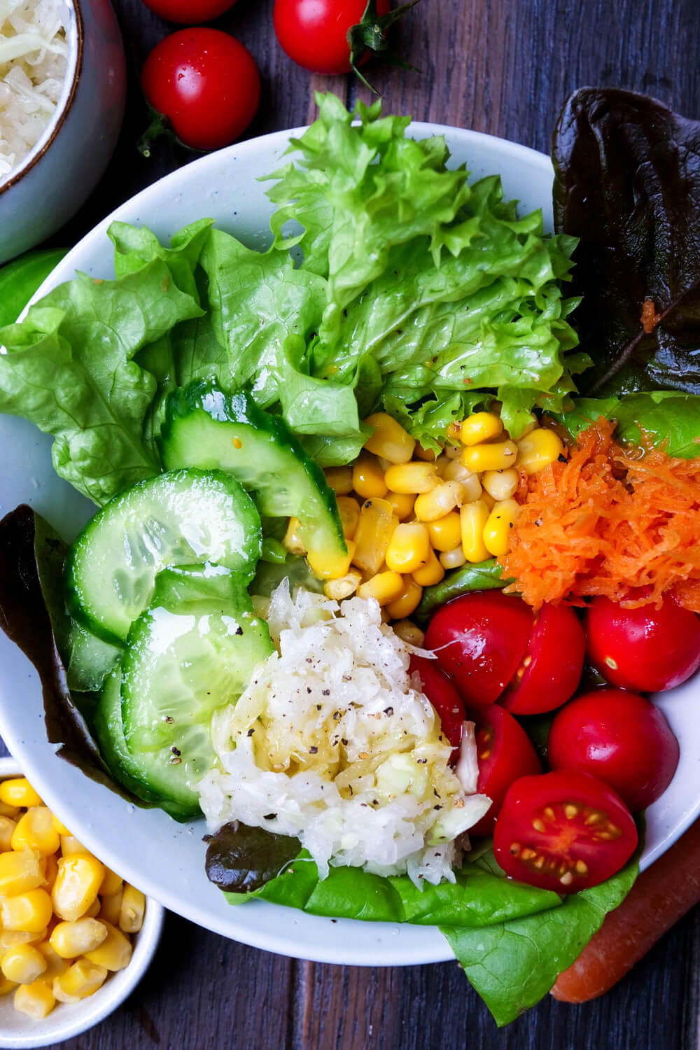 Salat als Beilage mit grünem Salat, Gurke, Tomaten, Möhren, Mais und Krautsalat