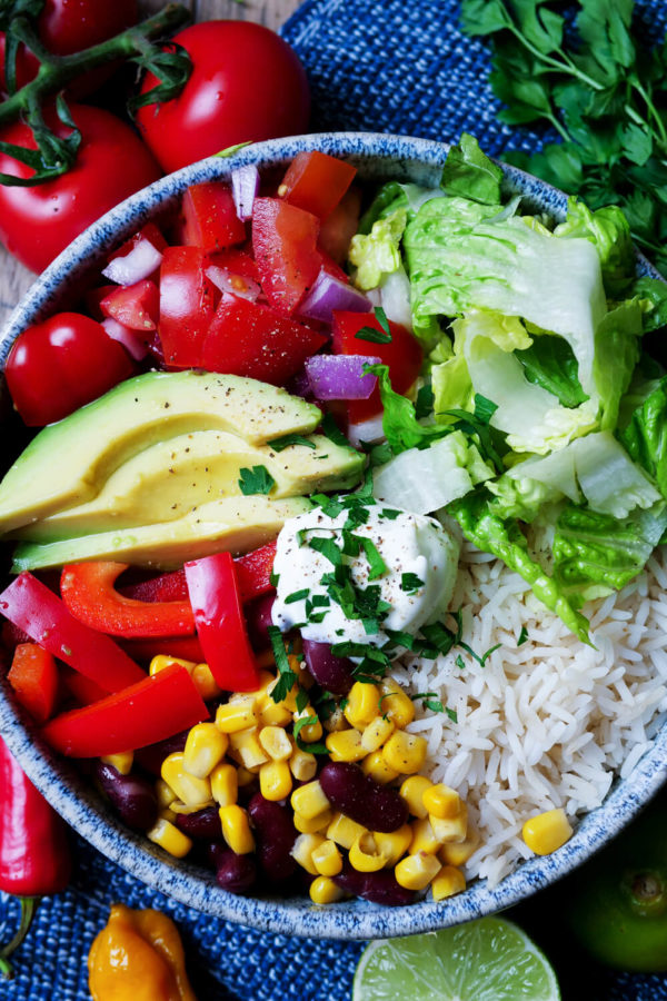 Vegetarische Burrito-Bowl mit Reis, Avocado, Paprika und Mais