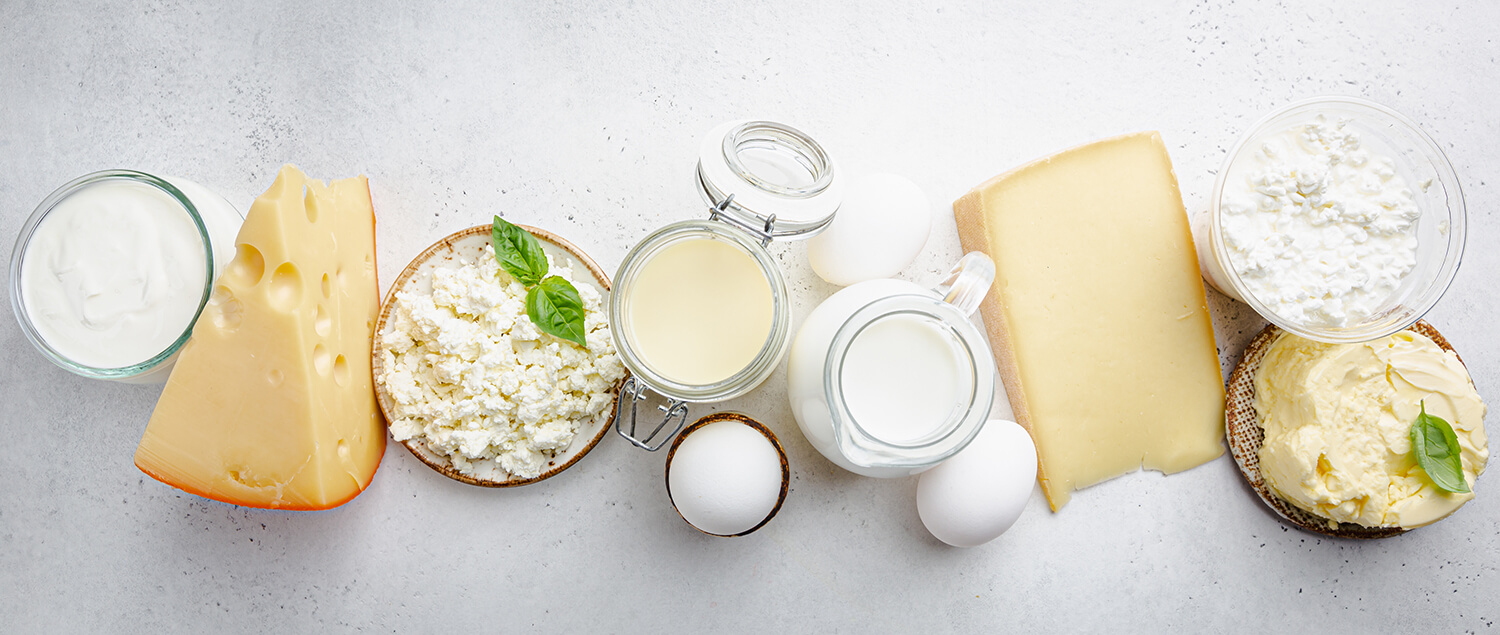 Verschiedene Milchprodukte wie Butter, Käse, Quark auf marmorierter Küchenplatte