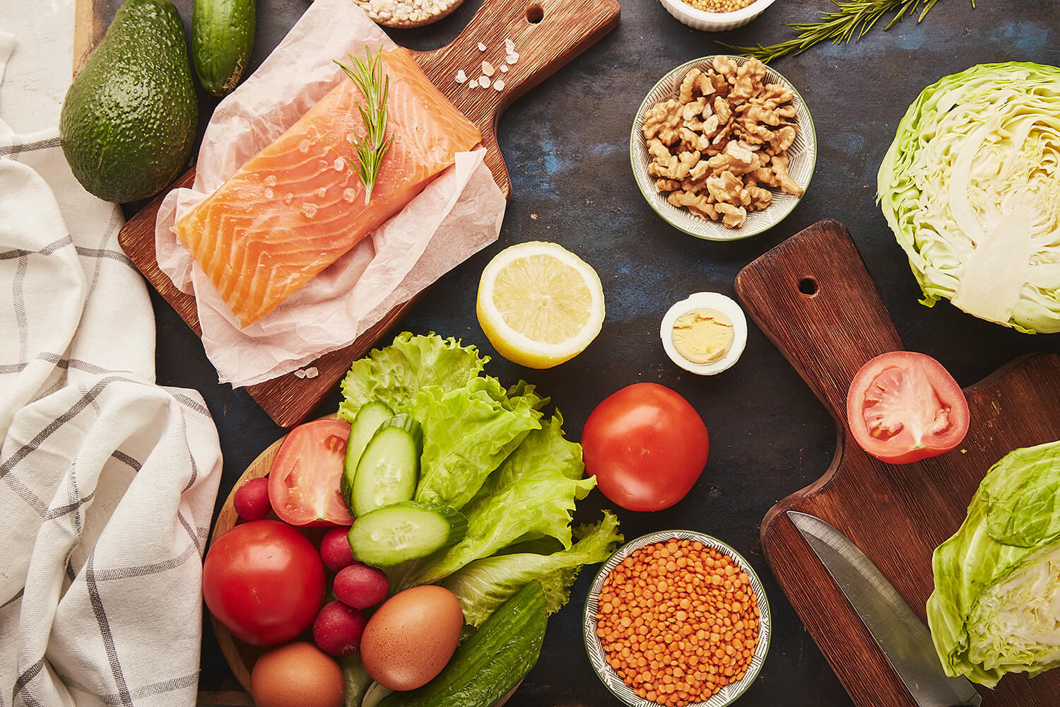Glutenfreie Lebensmittel - Gemüse, Obst, Walnüsse, geräucherter Lachs, Gemüse, Avocado - auf dunkler Tischplatte