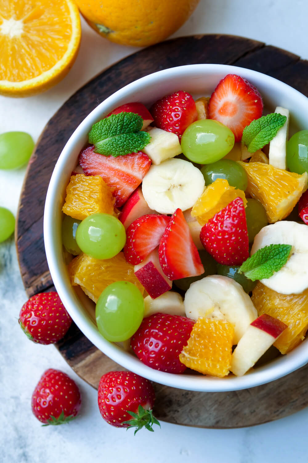 Bunter Obstsalat mit Orangen, Weintrauben, Erdbeeren, Banane und Apfel in der Schüssel
