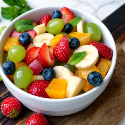 Obstsalat mit Orangen, Weintrauben, Erdbeeren, Banane, Heidelbeeren und Apfel in der Schüssel