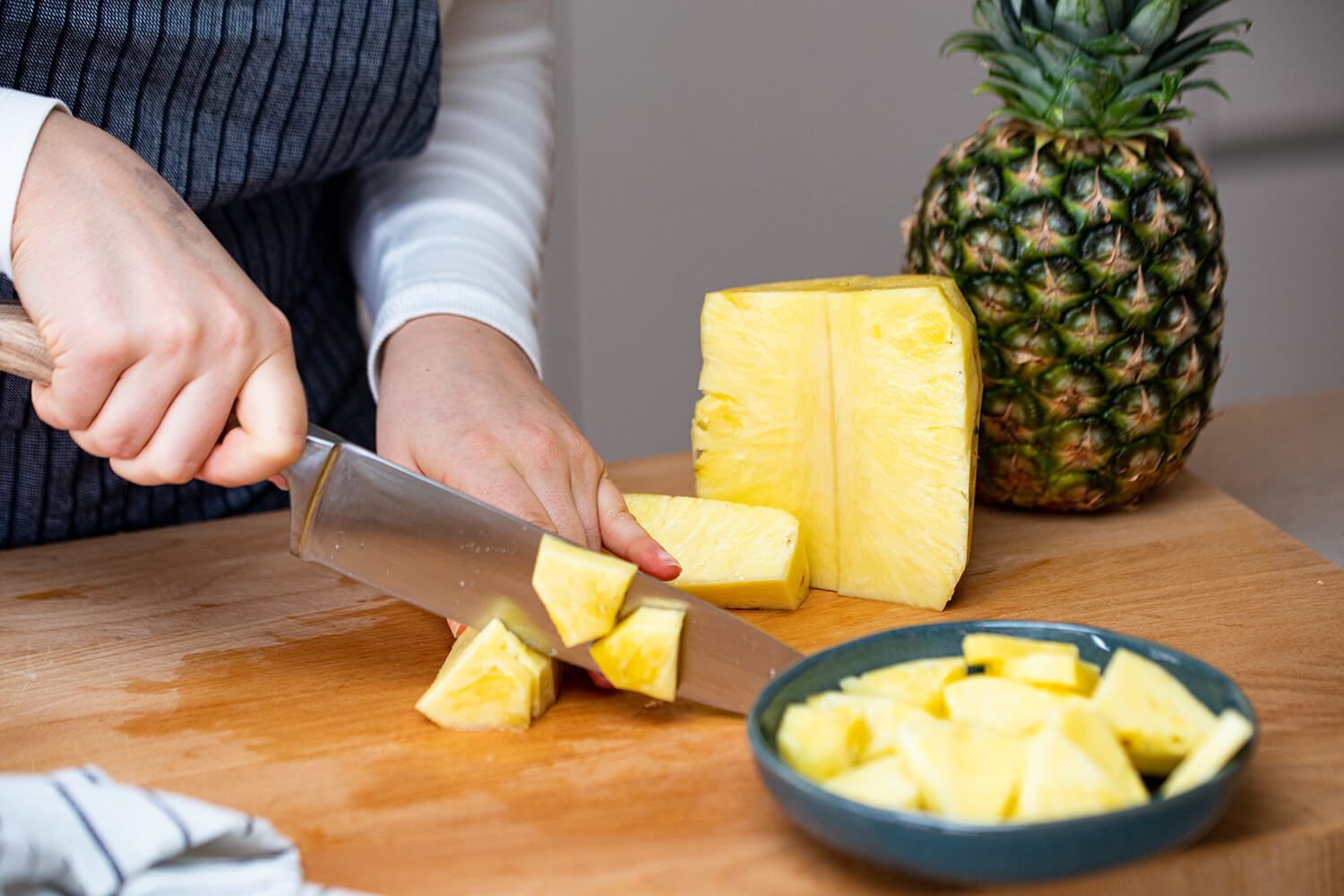 Das Fruchtfleisch einer Ananas wird in Würfel geschnitten