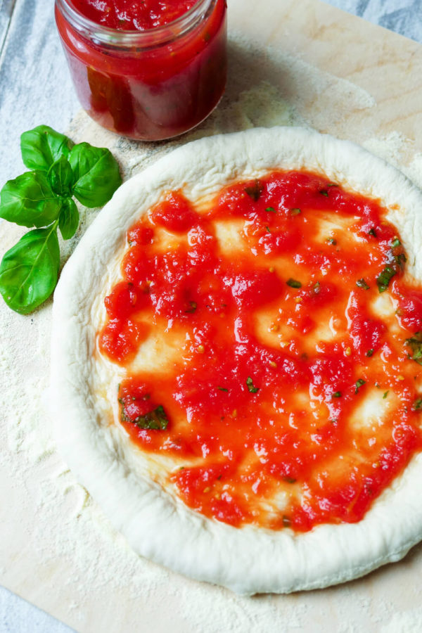 Pizzateig mit Tomatensauce besteichen