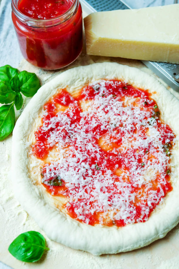 Pizzateig mit Tomatensauce und Parmesan belegt