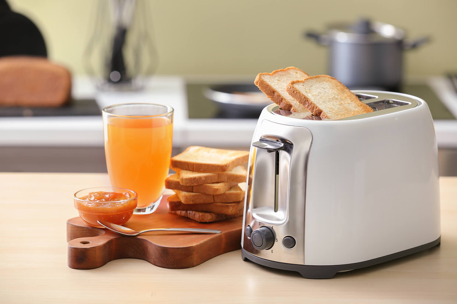 Toaster mit Brotscheiben und einem Glas Saft auf dem Tisch