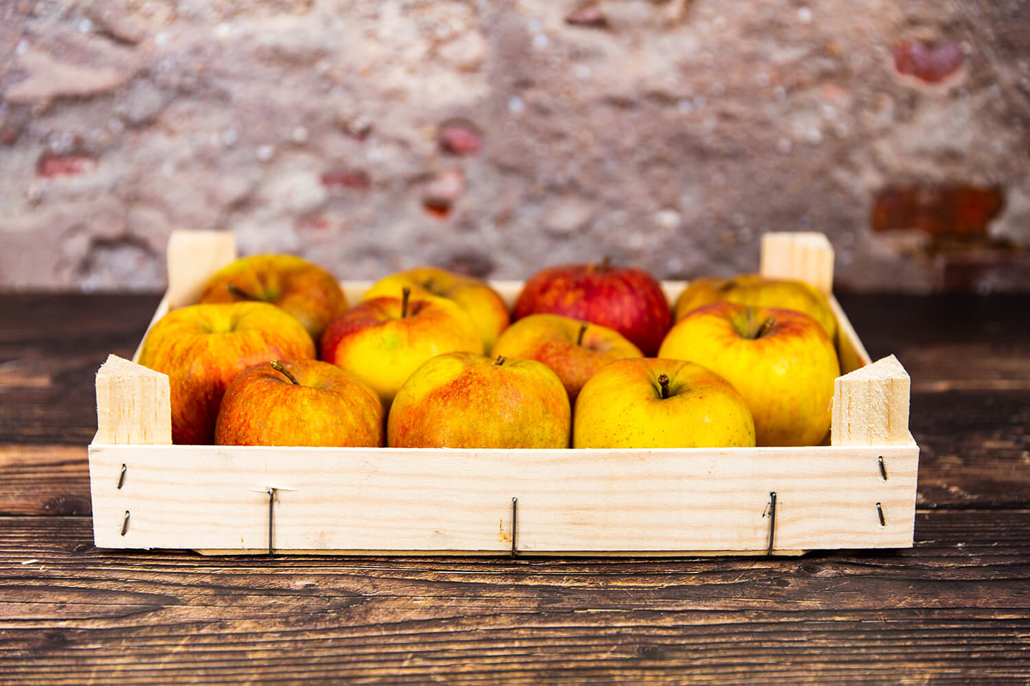 Gelbe Äpfel in Apfelkiste auf Holztisch