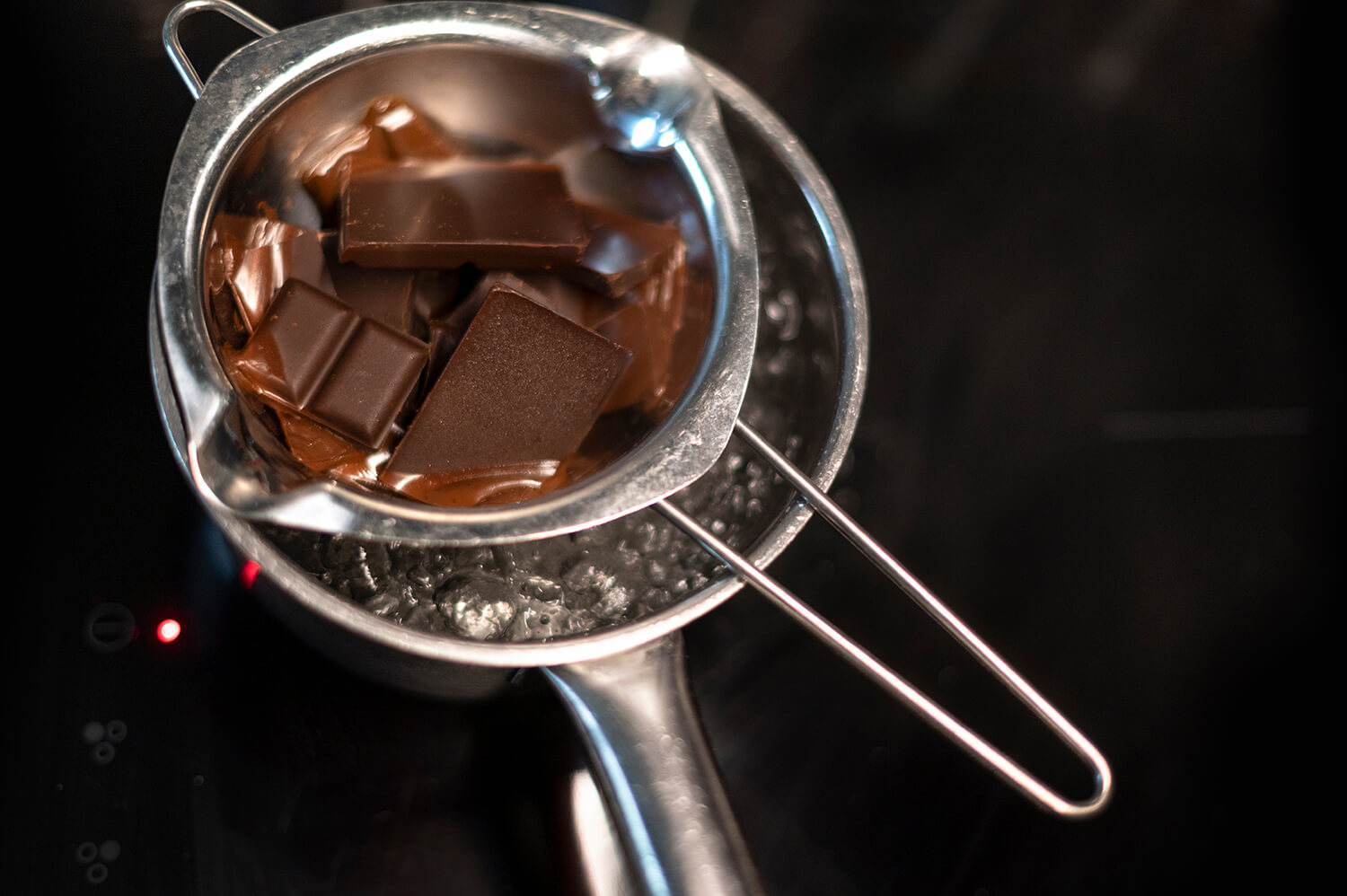 Schokolade wird mit Metallschale im Wasserbad geschmolzen
