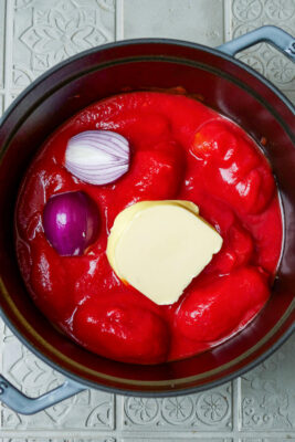 Geschälte Tomaten, Butter und Zwiebel im Topf