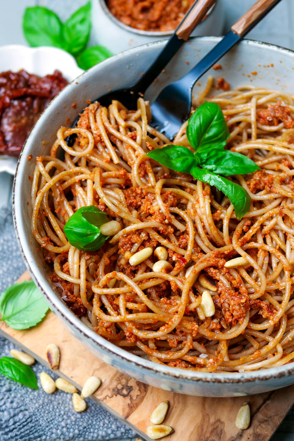 Spaghetti mit rotem Pesto Rosso, Basilikum und Pinienkernen auf dem Teller