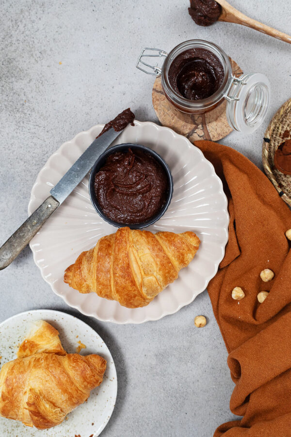 Selbstgemachte gesündere Nutella  in der Schale zu einem Croissant