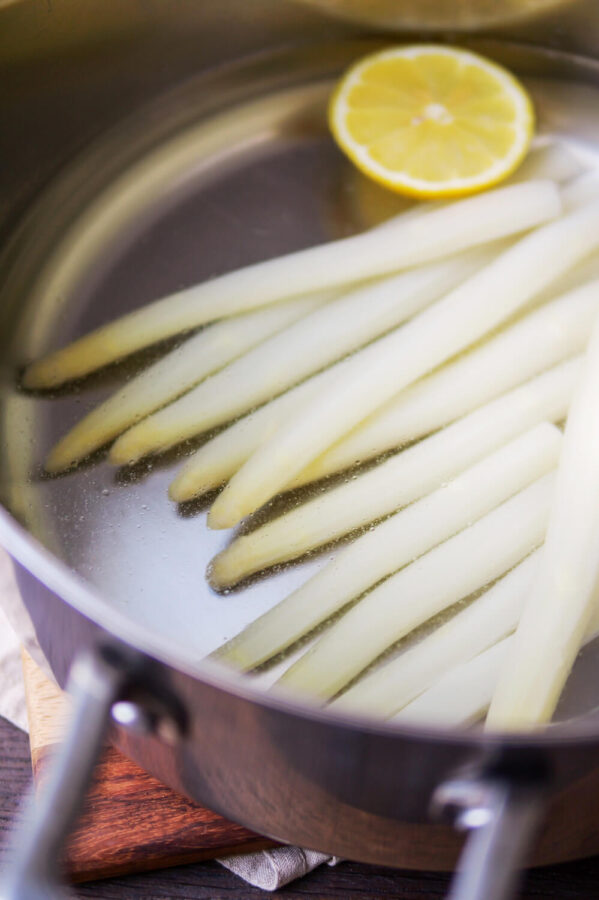 Weißer Spargel mit Zitrone in einem Kochtopf.