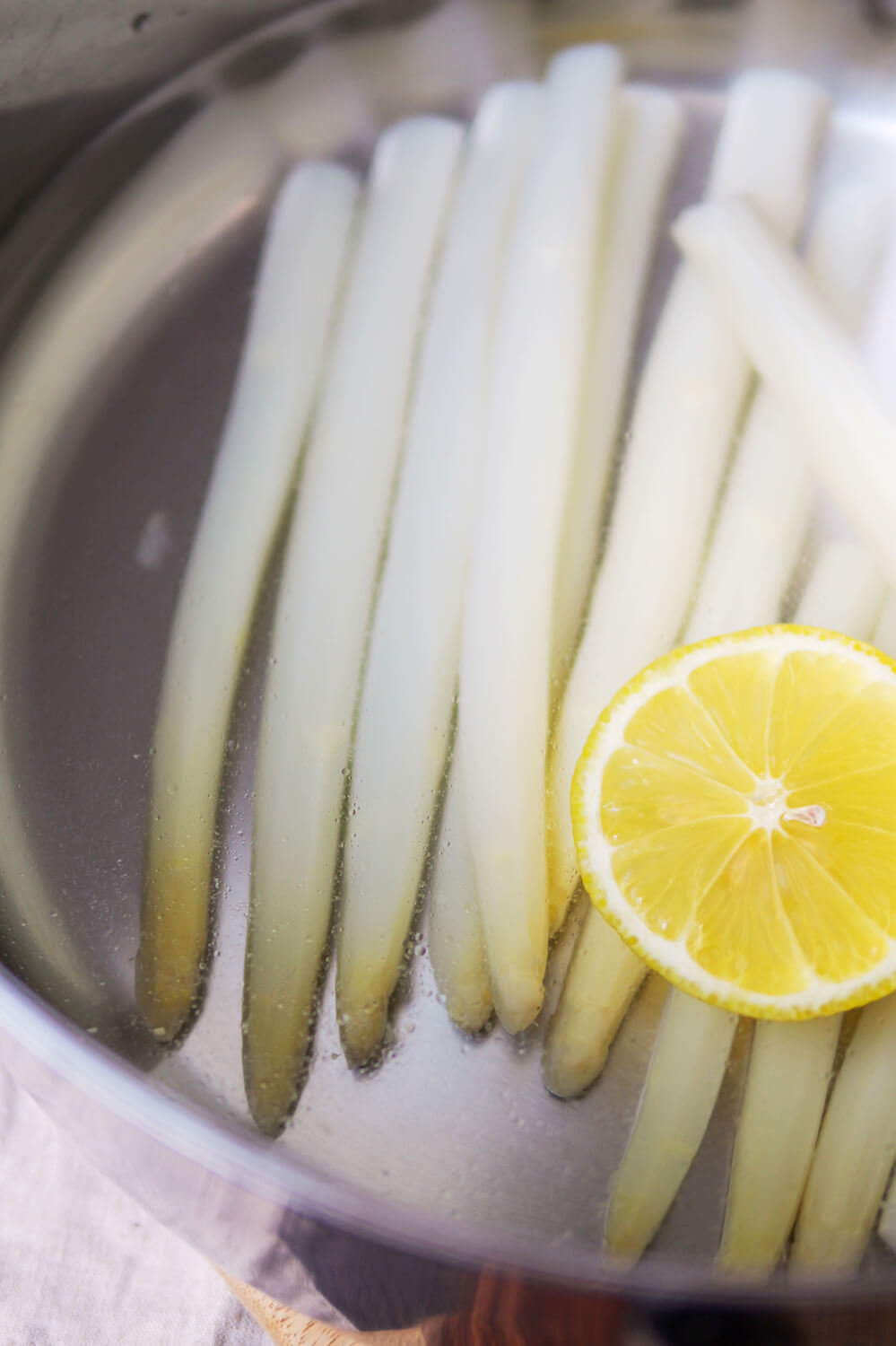 Weißer Spargel mit Zitrone in einem Kochtopf.