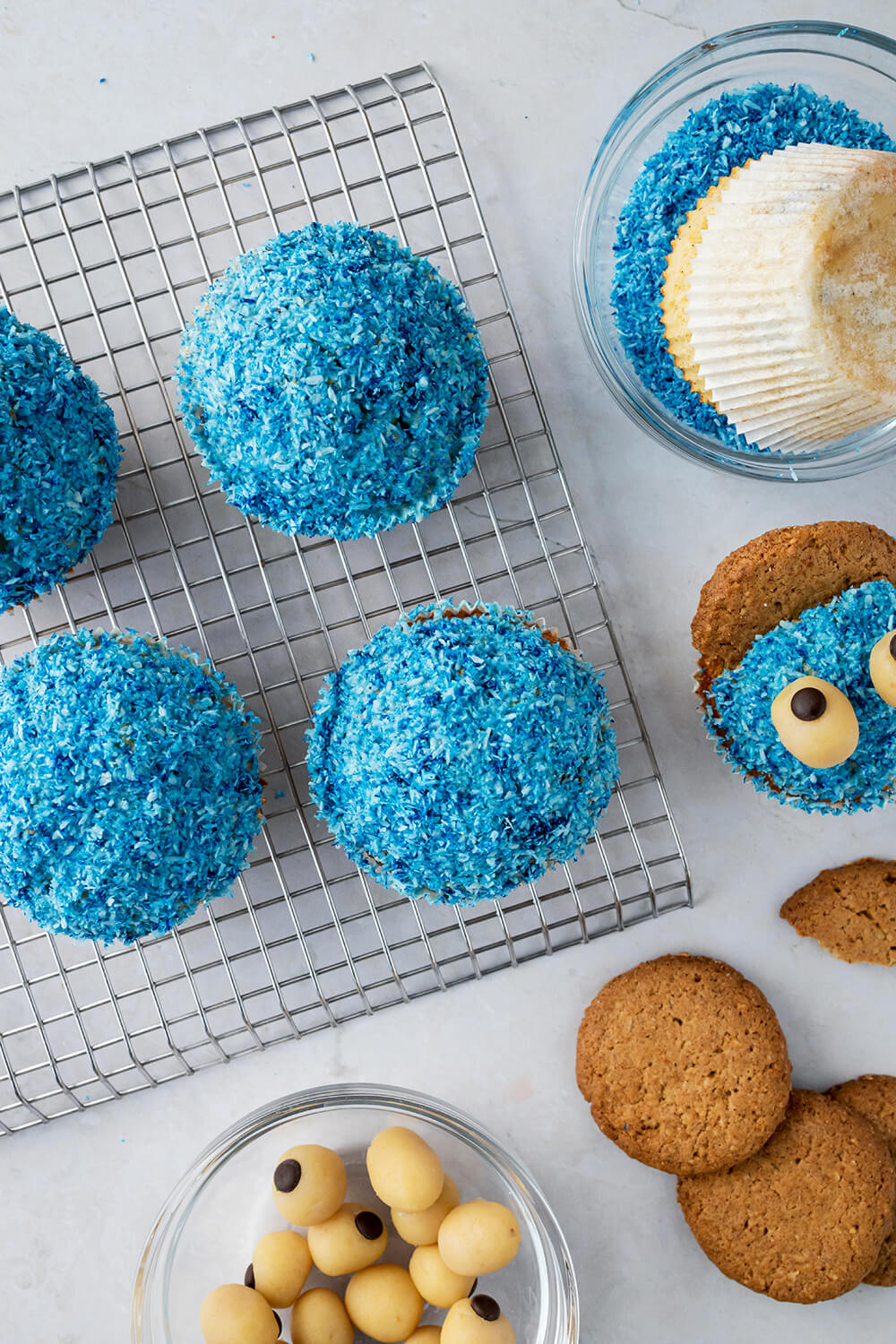 Vorbereitete, blaue Muffins als Basis für Krümelmonster-Muffins auf einem Kuchengitter.