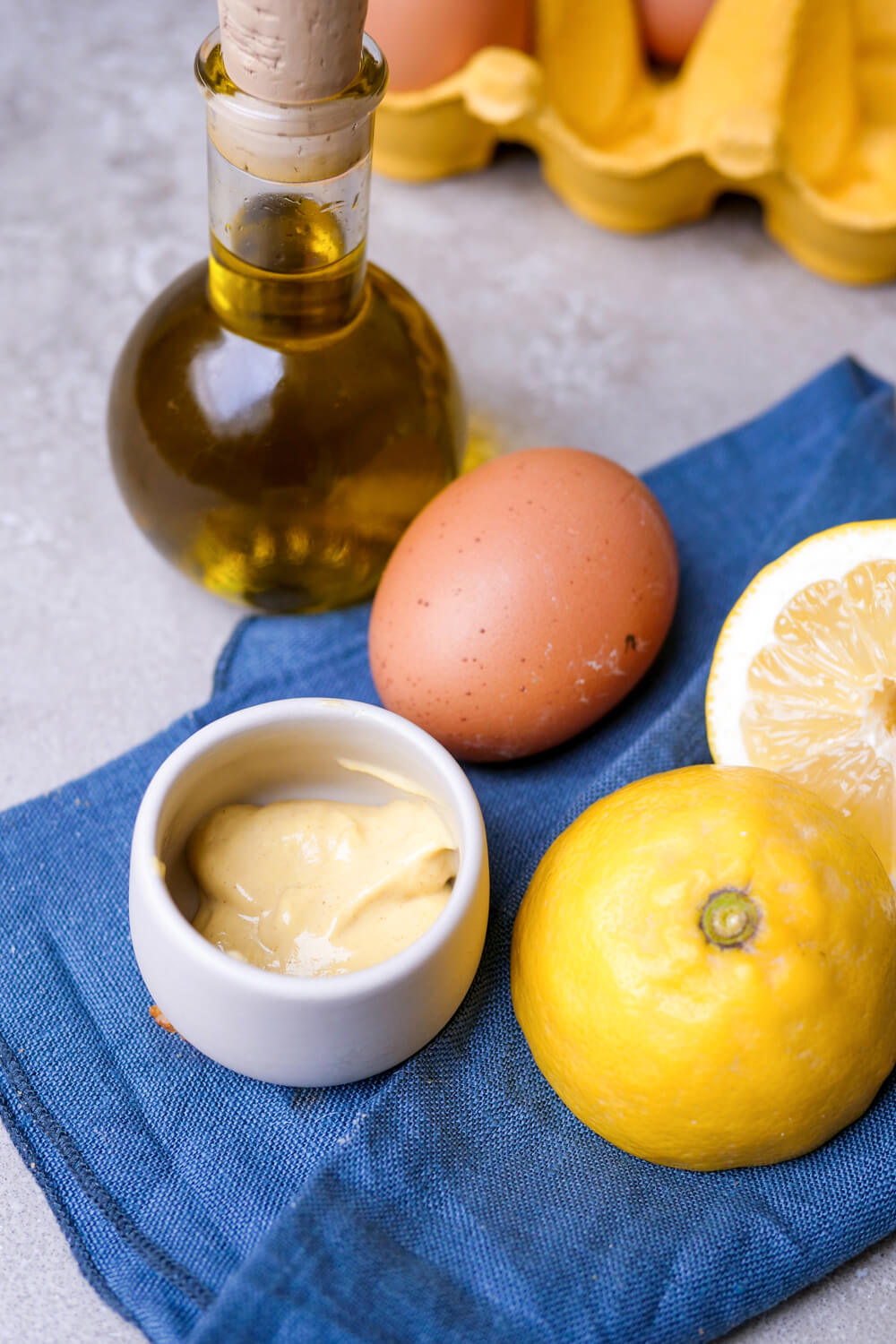 Senf, Ei, Öl, Zitrone auf einem blauen Tuch.